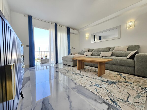 A modern living room with a grey sofa, wooden coffee table, and a marble-patterned rug.