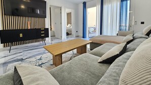 Ein modernes Wohnzimmer mit einem Flachbildfernseher, einem Holztisch und einer Sofagarnitur.
