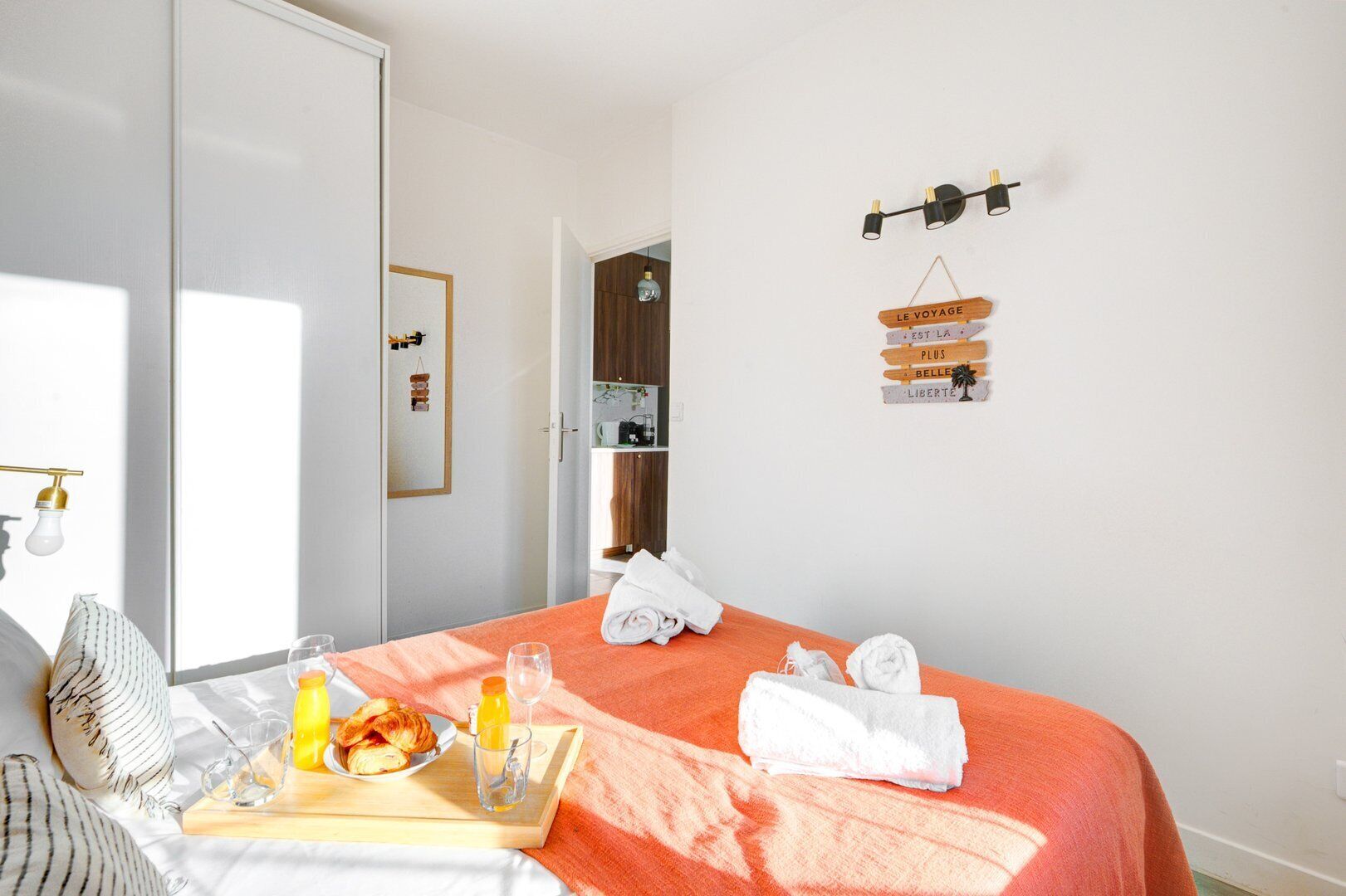 Hotelkamer met een bed, een ontbijfwagen met croissants en sinaasappelsap, een handdoek en een bord met Franse tekst.