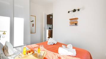 Hotelkamer met een bed, een ontbijfwagen met croissants en sinaasappelsap, een handdoek en een bord met Franse tekst.