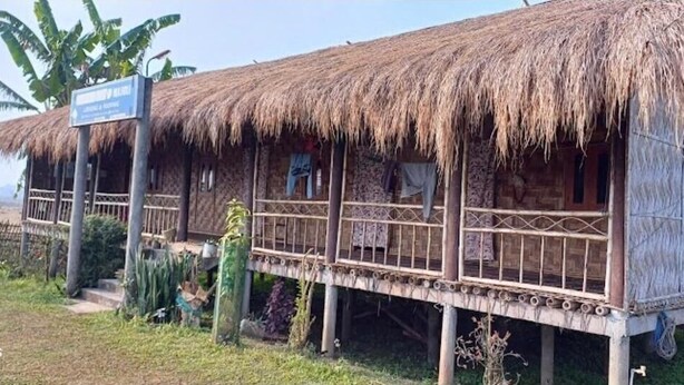 A thatched-roof structure with a balcony, a signboard, and a view of the sea. - Sarangi Stay By GRB (Majbat)