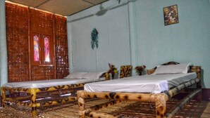 A room with two beds, a large window with curtains, and a wall-mounted decoration. - Sarangi Stay By GRB (Majbat)
