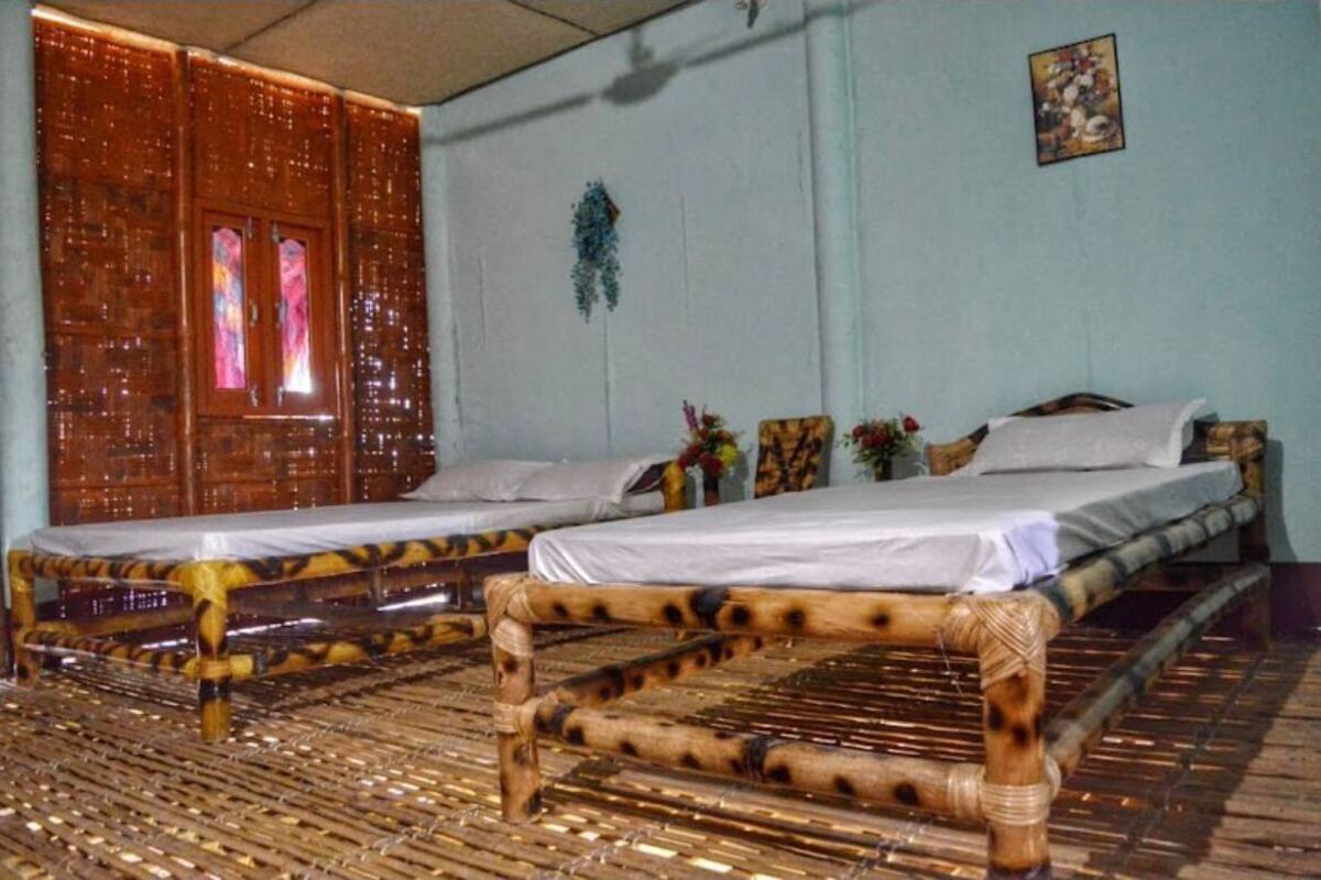 Een kamer met twee bedden, een groot raam met gordijnen en een decoratie aan de muur.