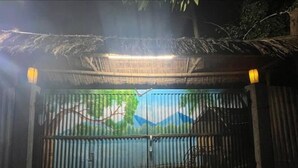 A gated entrance with a metal gate and a decorative backdrop. - Sarangi Stay By GRB (Majbat)