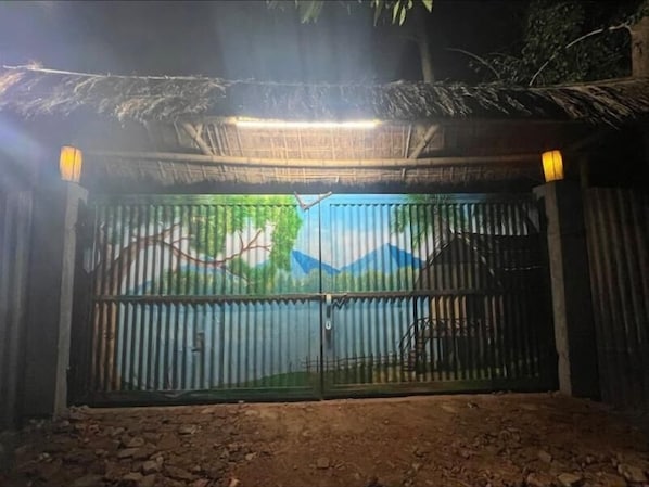 A gated entrance with a metal gate and a decorative backdrop. - Sarangi Stay By GRB (Majbat)