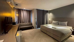 Ein modernes Hotelzimmer mit Bett, Schreibtisch, Fernseher und Klimaanlage.