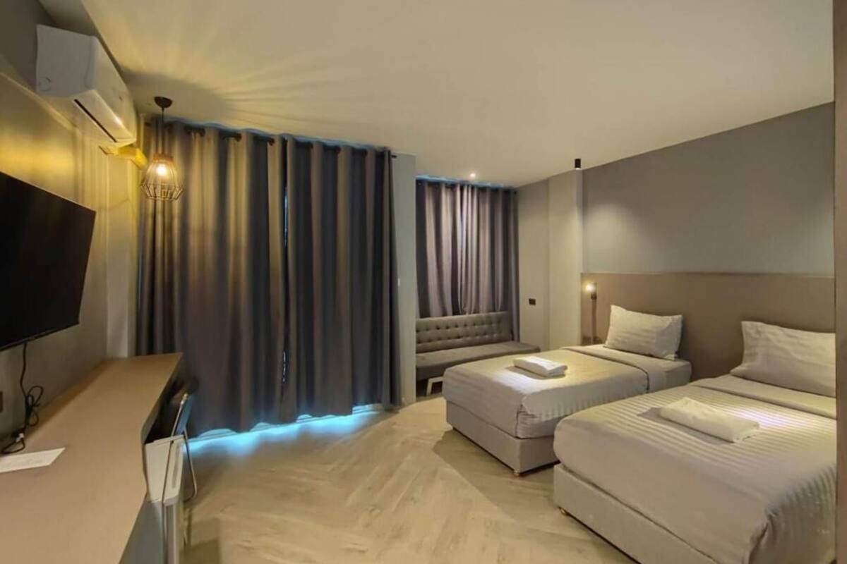 A hotel room with a bed, a sofa, a desk, and a television.