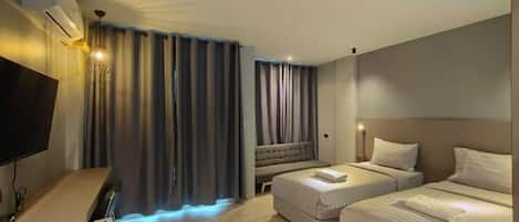 A hotel room with a bed, a sofa, a desk, and a television.