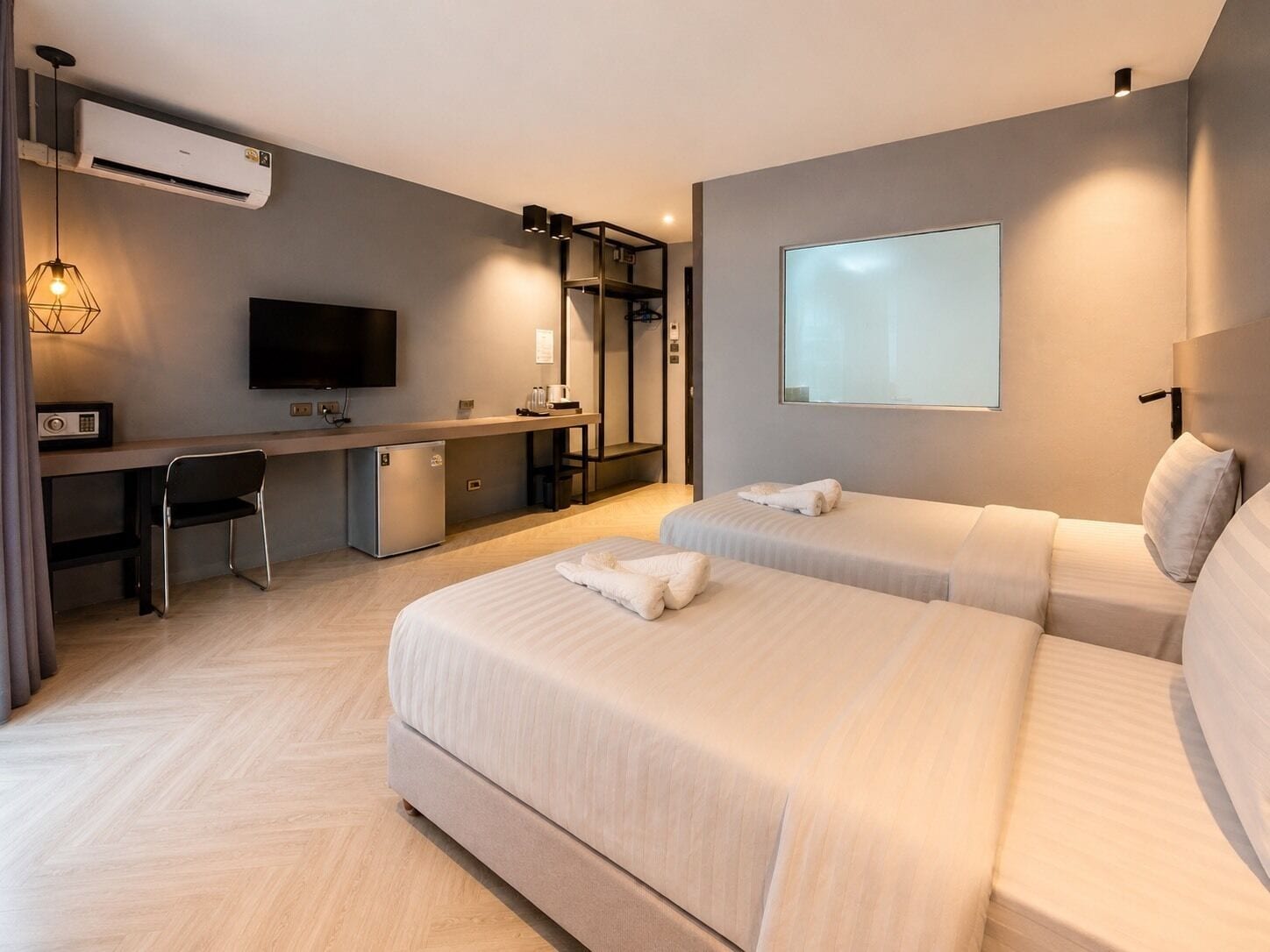 A modern hotel room with a bed, a desk, a television, and a projector screen.