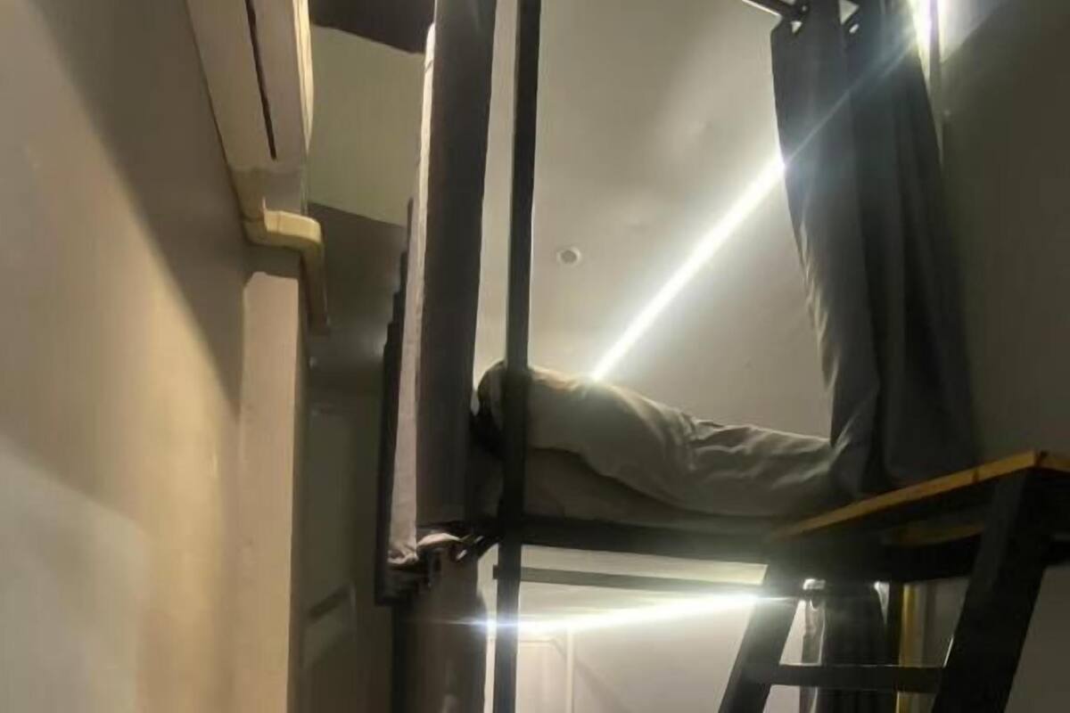 A bunk bed with a ladder, a curtain, and a small window.