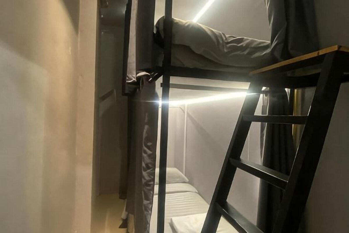 A bunk bed with a ladder, a mattress, and a headboard.