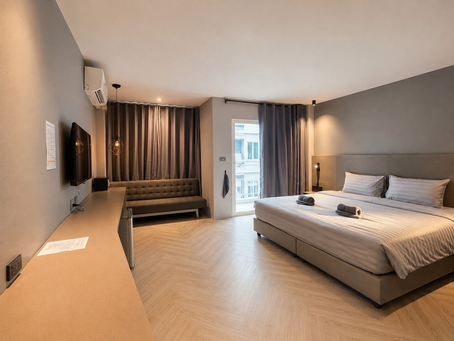 A modern hotel room with a large bed, a seating area, and a television.