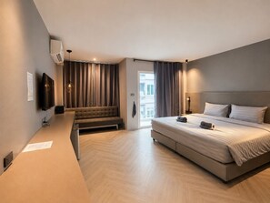 A modern hotel room with a large bed, a seating area, and a television. - Doze Patong (Patong)