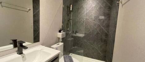 Een moderne badkamer met een wit wastafel, toilet en een douche met glazen wanden.