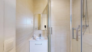 A modern bathroom with a glass shower enclosure, a white sink with a mirror, and a small cabinet. - TBS 141 - Bright and elegant apartment (Paris)