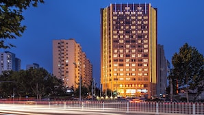 Un hotel a più piani con una facciata moderna, finestre illuminate e un ingresso ben visibile.