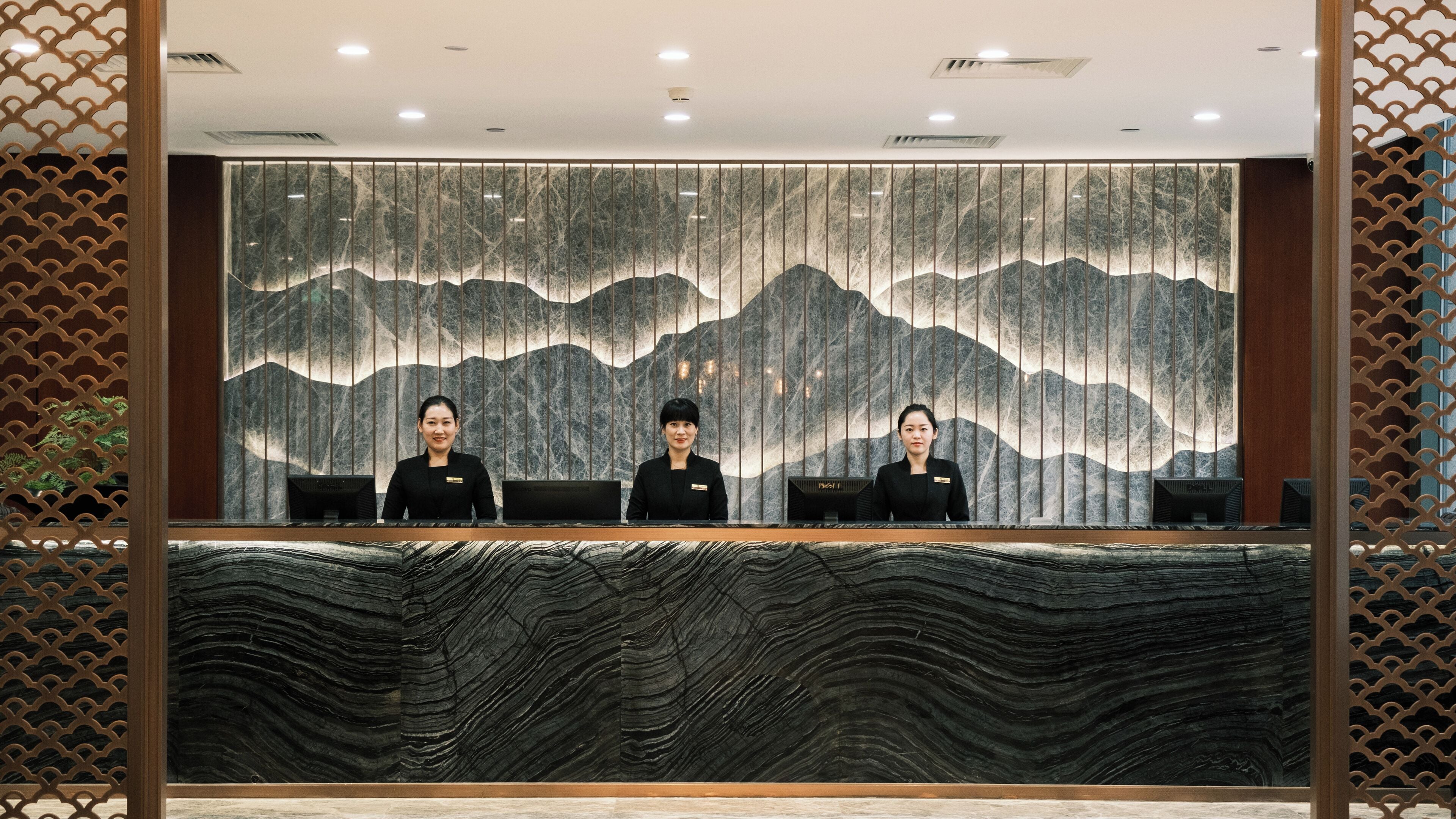 Un mostrador de recepción con un fondo de pared de mármol y un mostrador de madera.