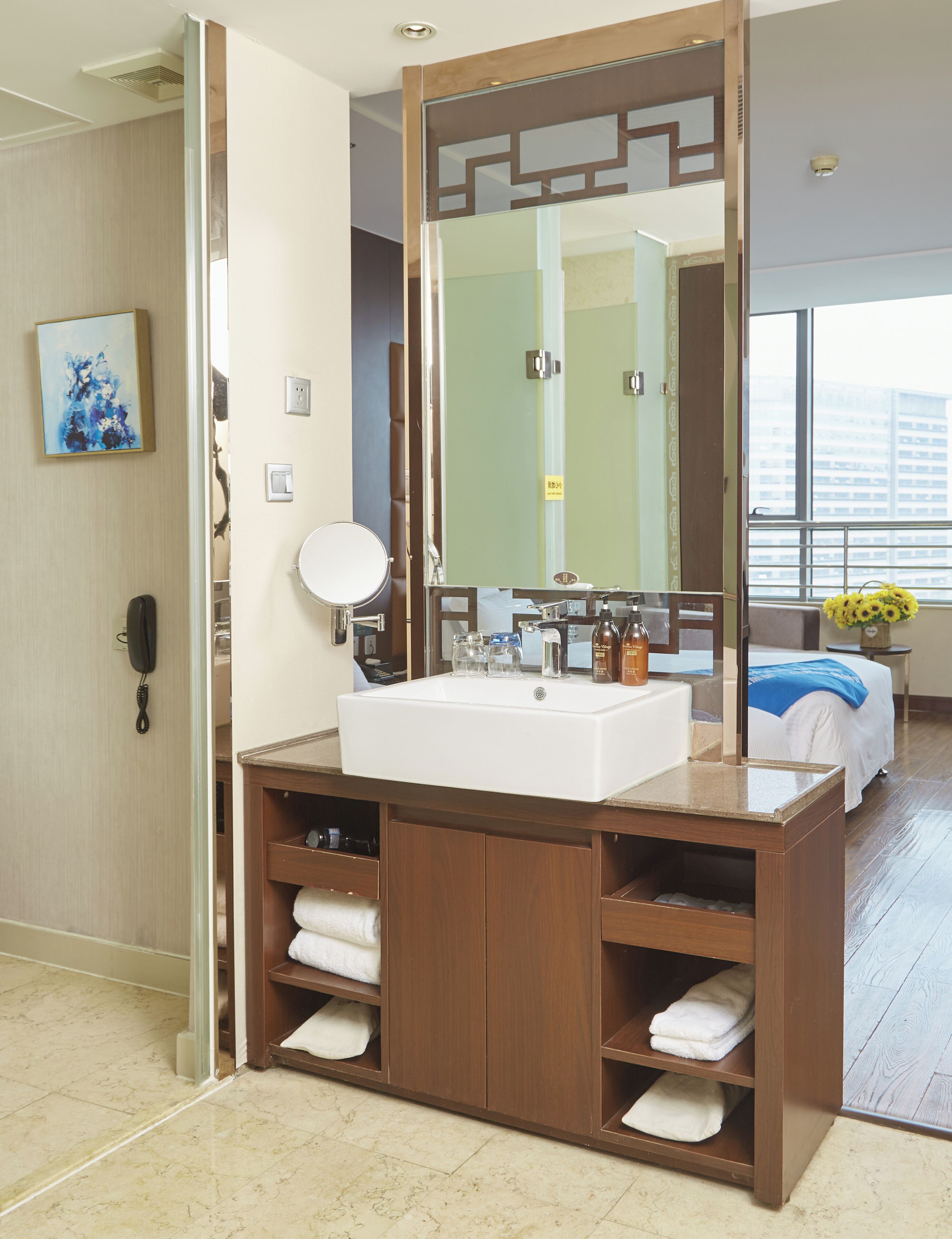 A modern bathroom with a large mirror, a white sink, and wooden cabinets.