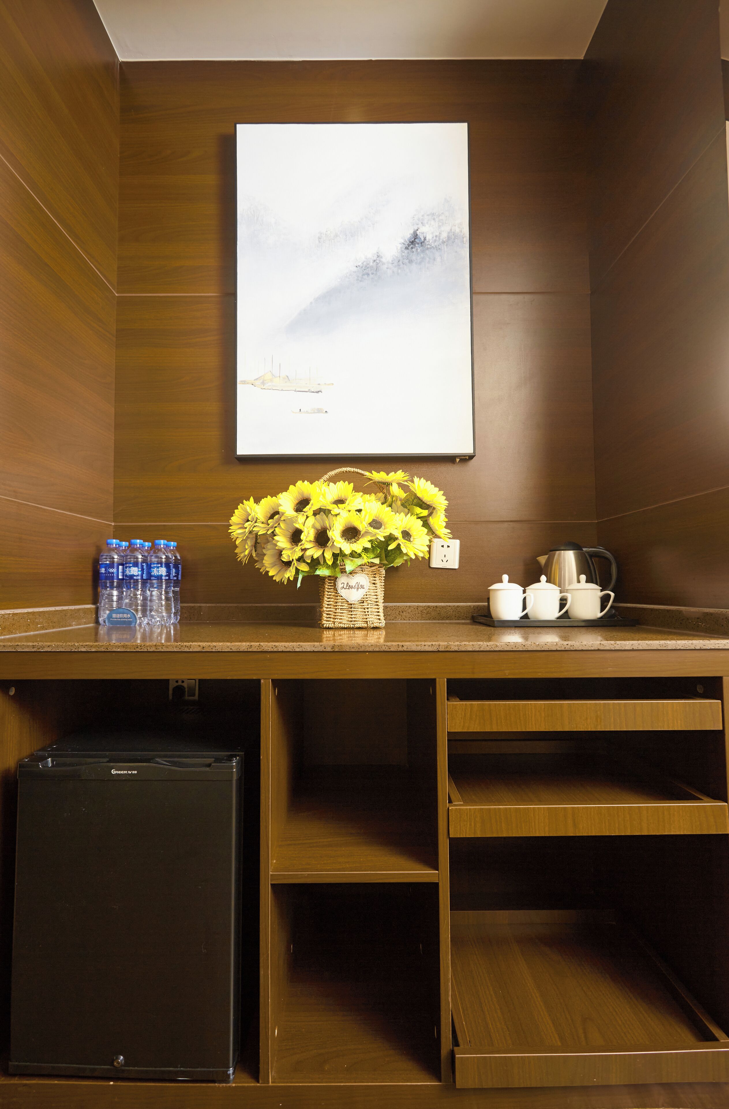 A wooden counter with a vase of sunflowers, a basket, and a coffee maker.