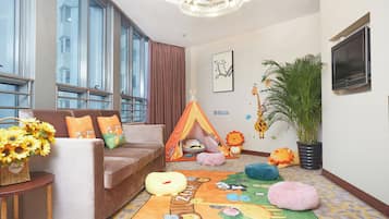 A cozy room with a brown sofa, a small table with a basket of sunflowers, a tent, and plush animal toys.