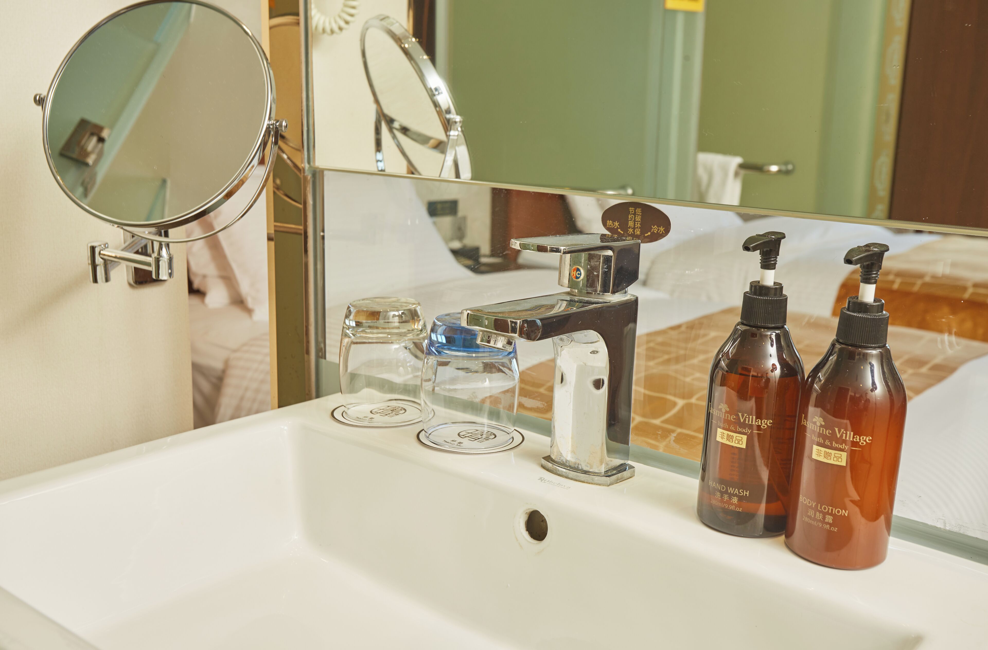A bathroom sink with a mirror, a faucet, and two bottles of body lotion.