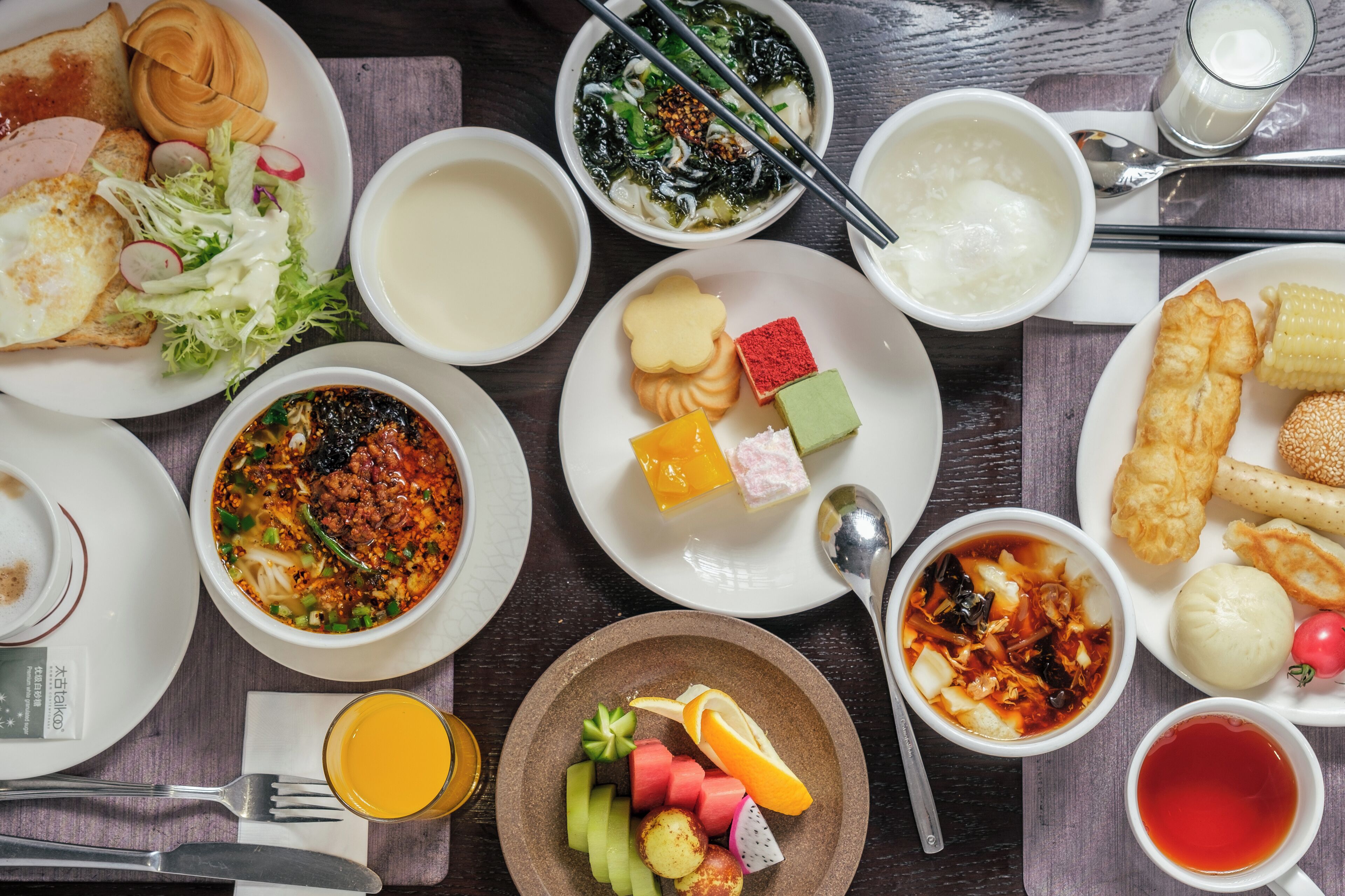 A variety of dishes including soup, rice, and vegetables on a wooden table.