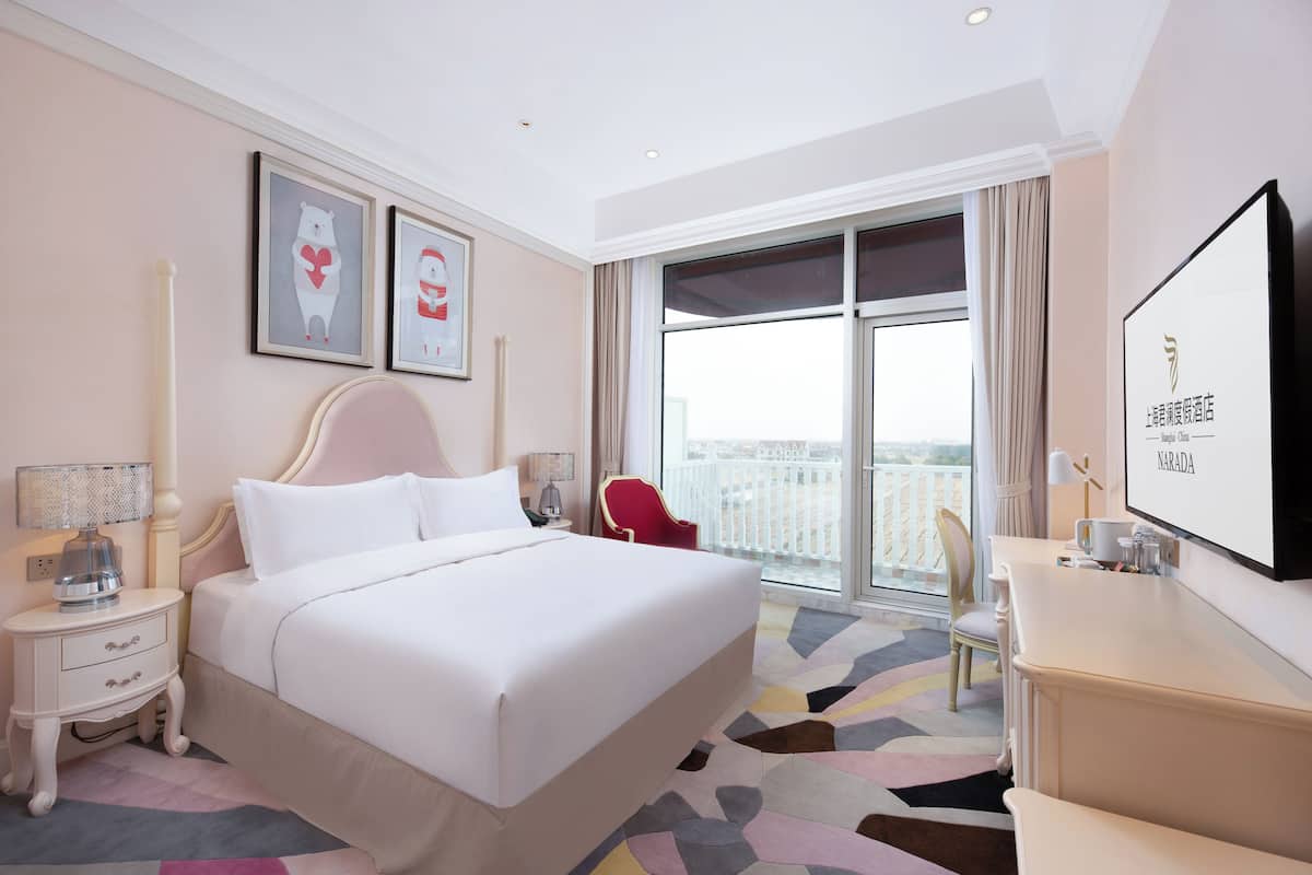 Une chambre d’hôtel avec un grand lit, un bureau, une chaise, une télévision et un balcon avec vue.