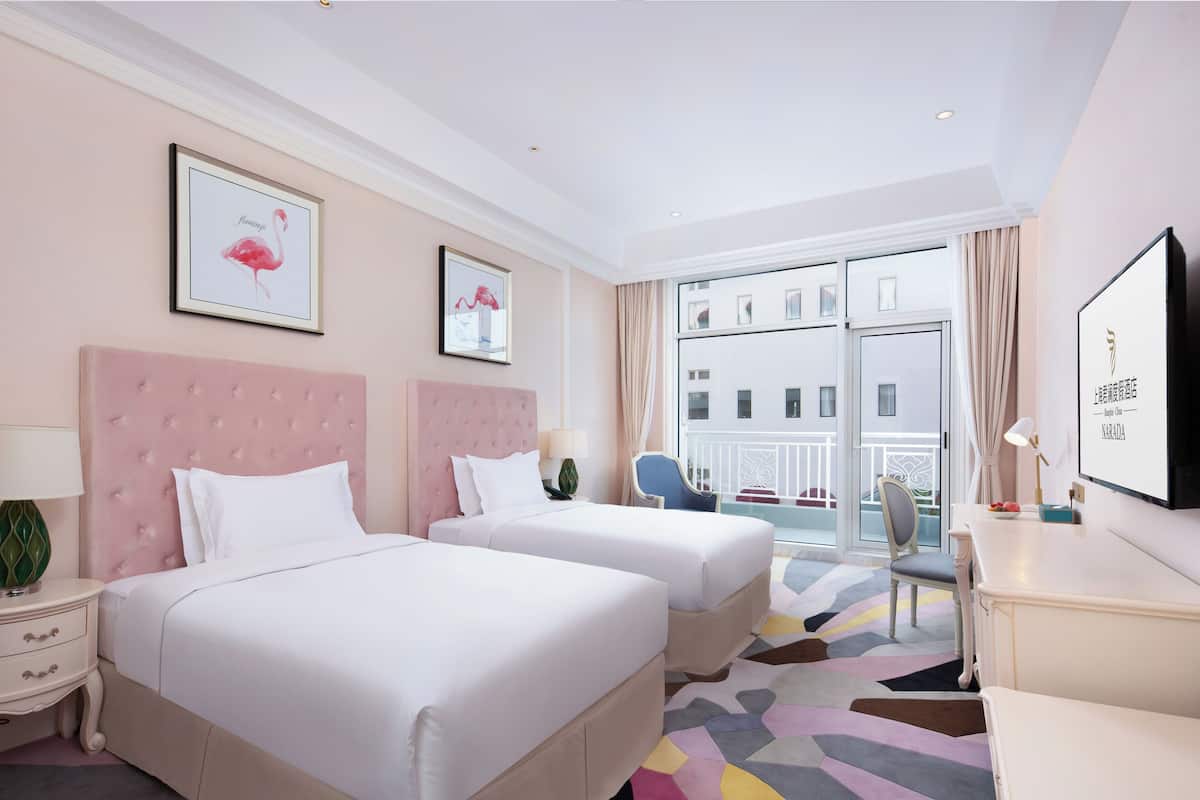 Une chambre d’hôtel avec deux lits, un bureau, une chaise et un balcon avec vue.