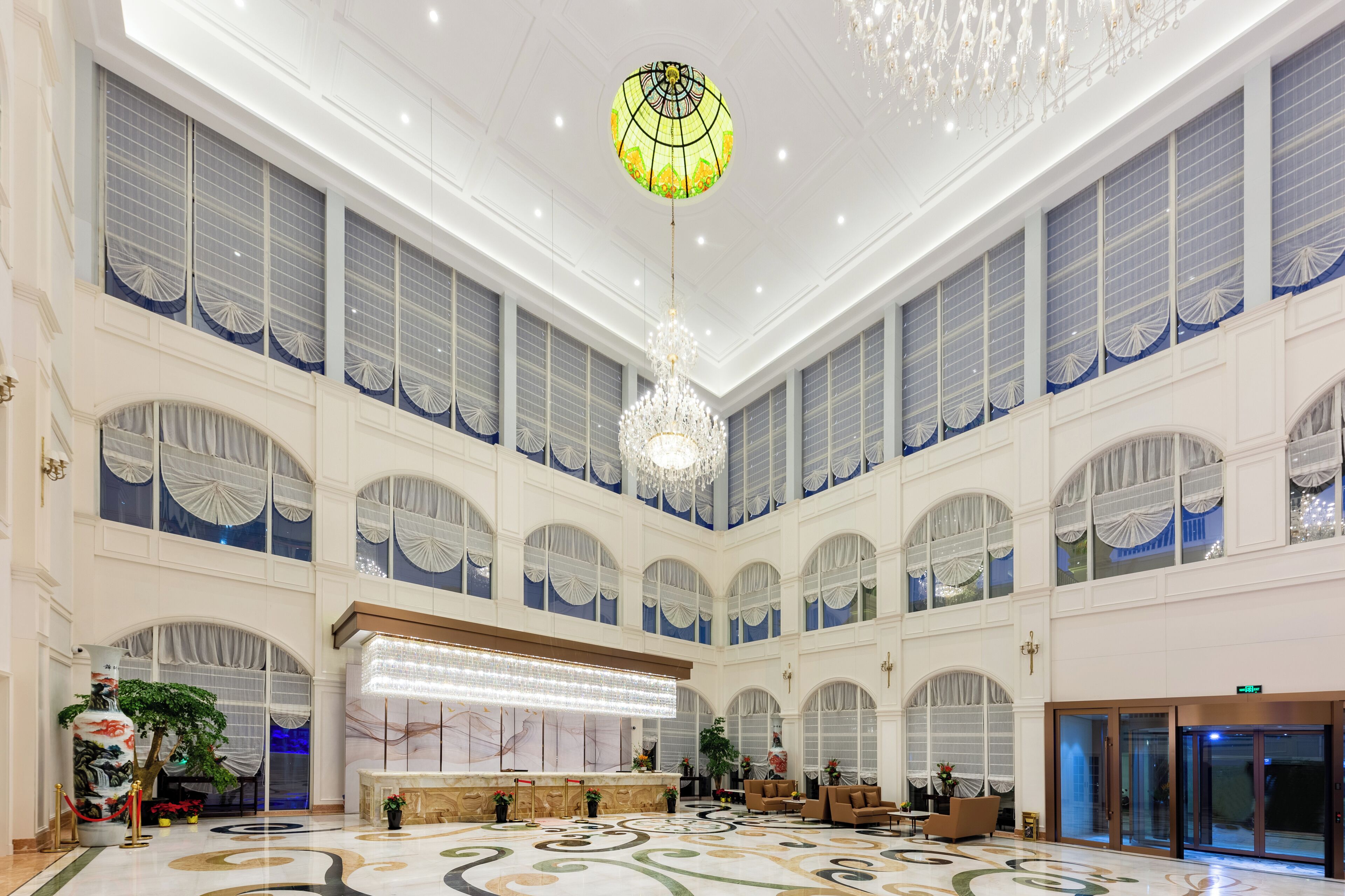A spacious lobby with a reception desk, seating area, and a large chandelier.