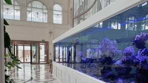 A spacious lobby with a large aquarium, high ceilings, and a marble floor. - NARADA RESORT SHANGHAI  HOTEL Disney Store (Shanghai)