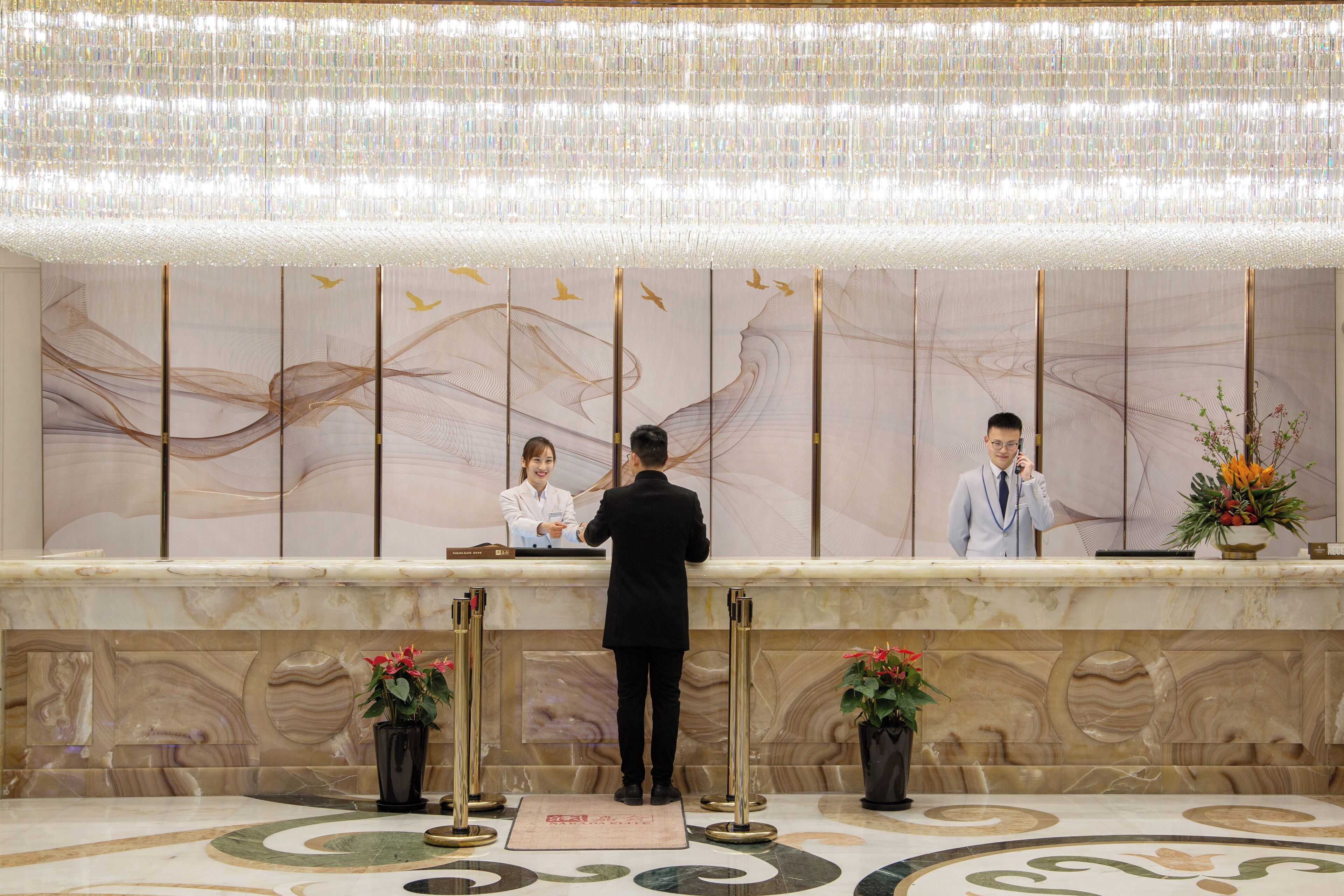 A reception area with a marble counter, gold accents, and a large wall mural with abstract designs.