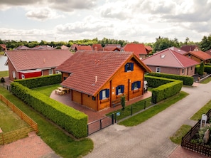 Et boligområde med huse, røde tegltage, velplejede hække og en belagt indkørsel.