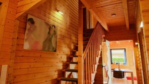 A wooden interior with a staircase, a painting on the wall, and a window with a view. - Holiday Home 'Auszeit Am See' with Lake View, Private Terrace and Wi-Fi (Walchum)