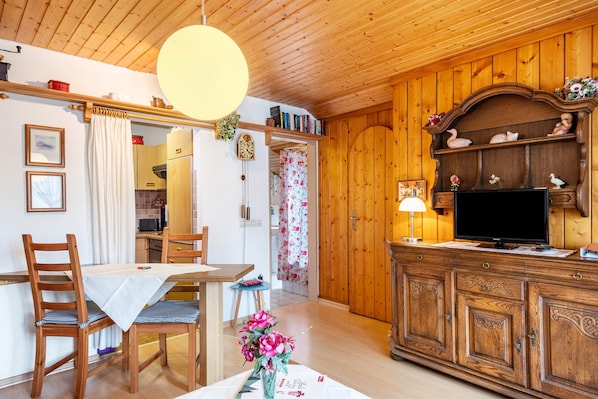 A wooden-paneled room with a dining table, chairs, a TV, and a cabinet.