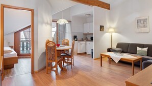 Quarto com mesa de jantar, cadeiras, sofá, luminária e área de cozinha.
