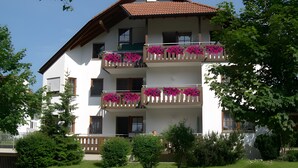 Un immeuble à plusieurs étages doté de balcons, d’un toit en pente et d’un espace jardin.