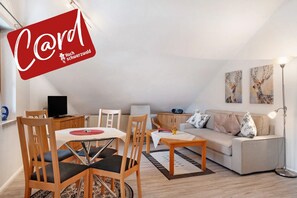 Un salon moderne avec une table à manger, des chaises, un canapé et des œuvres d’art accrochées aux murs.