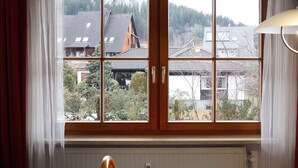 Une pièce dotée d’une grande fenêtre, de volets en bois et d’un radiateur situé en dessous.