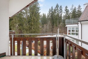 A balcony with a wooden railing, overlooking a garden with potted plants and trees. - Apartment 'Nr 8' with Balcony and Wi-Fi (Titisee-Neustadt)