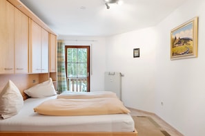 Une chambre à coucher avec un lit, des armoires en bois, un radiateur, une fenêtre avec des rideaux et un tableau accroché au mur.