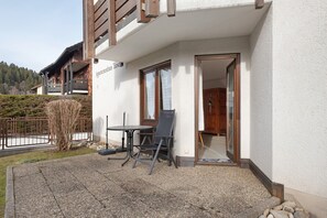 Un bâtiment doté d’un balcon, d’une table avec des chaises et d’une porte donnant sur l’intérieur.