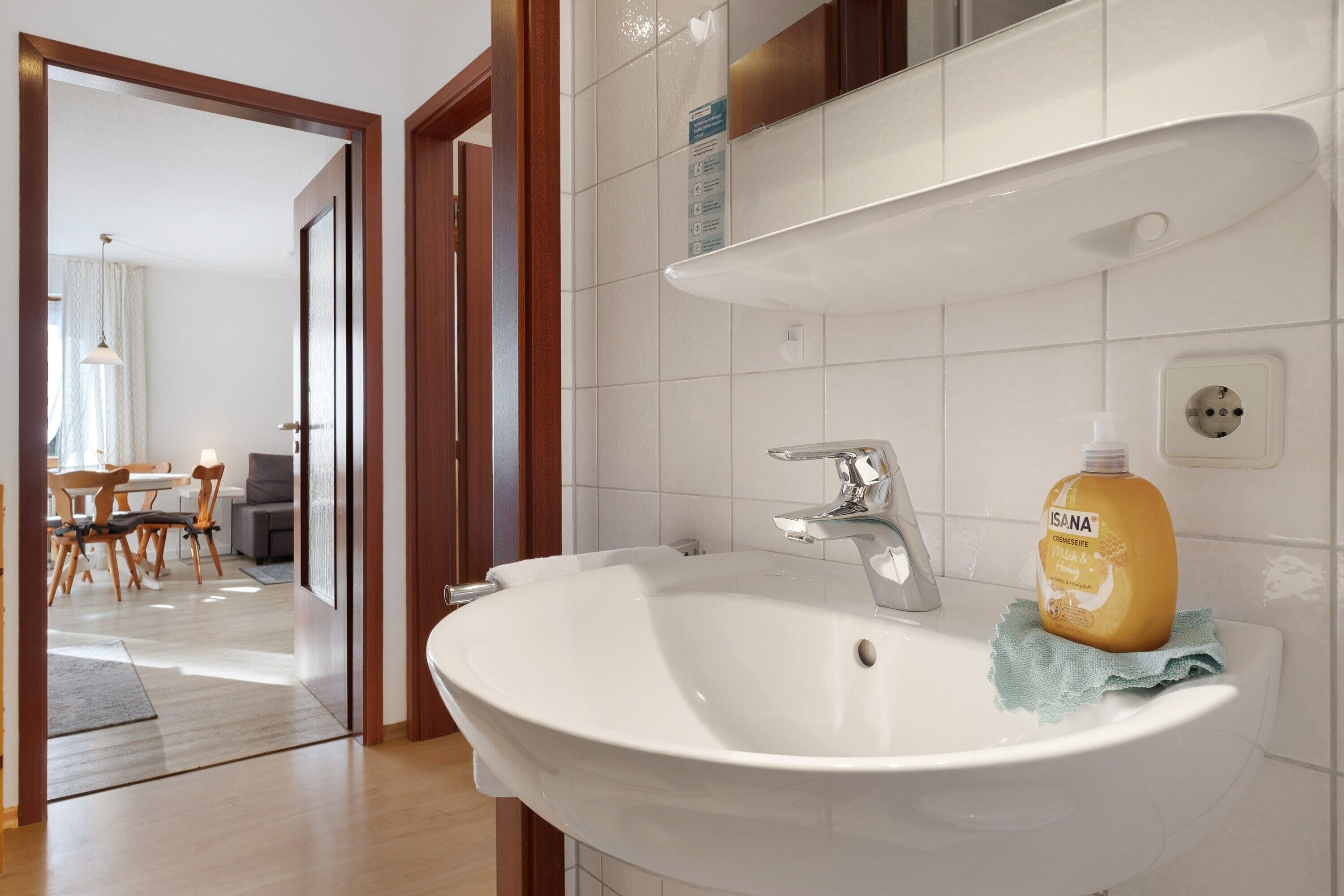 Un baño con un lavamanos blanco, una botella de jabón para manos y una toalla.