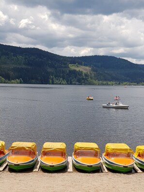 Un lago con barcos amarrados en primer plano y un barco a lo lejos.