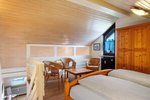 Een slaapkamer met een houten plafond, een bed, een tafel en rieten stoelen.