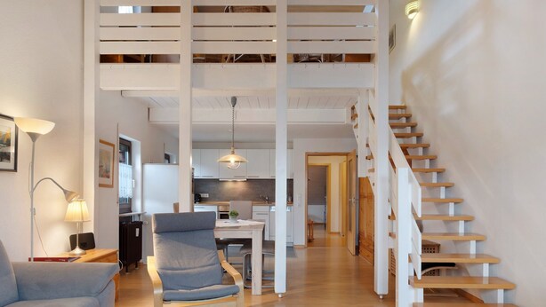 Un intérieur moderne comprenant un escalier, un coin repas et un salon avec un canapé et une lampe.