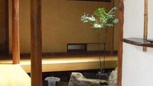 Una habitación japonesa tradicional con suelo de tatami, pilares de madera y un pequeño jardín de rocas.