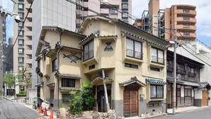 Un edificio japonés tradicional con varios balcones, un techo de tejas y un sendero de piedra que conduce a la entrada.