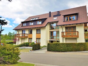 A multi-story residential building with a red-tiled roof, multiple balconies, and a well-maintained garden. - Apartment 'Nr 1c' with Private Terrace and Wi-Fi (Titisee-Neustadt)