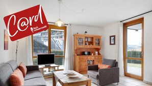 A modern living room with a sofa, armchair, TV, wooden cabinet, and a table. - Apartment 'Nr 1c' with Private Terrace and Wi-Fi (Titisee-Neustadt)