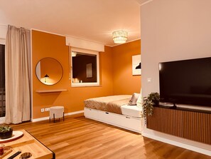 A modern bedroom with a bed, a TV, a window, and a mirror.